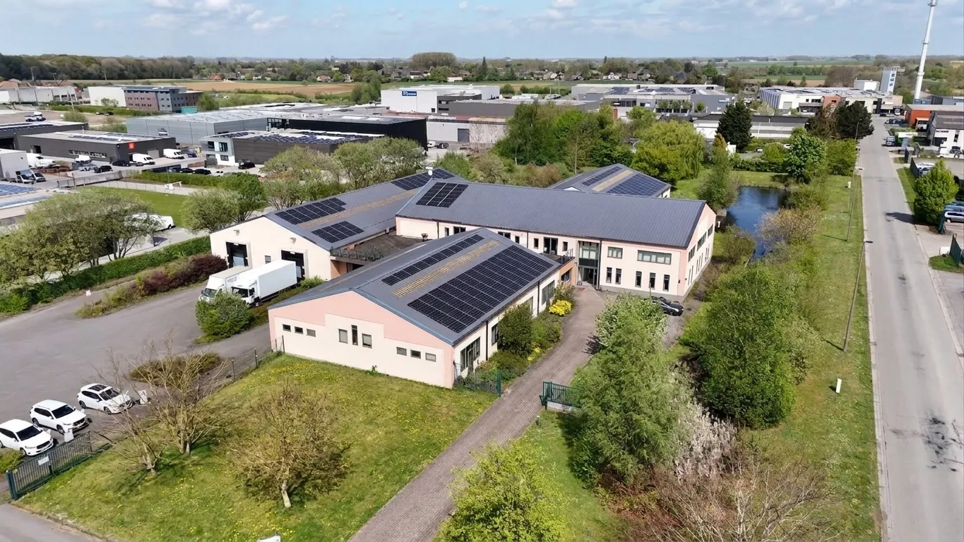 Vue aérienne du site de Priminfo à Noville-les-Bois : bâtiments en L, toitures couvertes de panneaux photovoltaïques.
